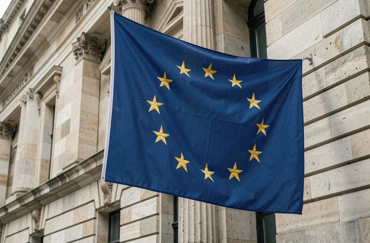 Drapeau européen à douze étoiles dorées accroché à la façade d'un bâtiment officiel en pierre, symbole de l'Union européenne